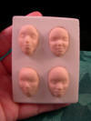 four doll faces in a mold