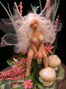 Dollhouse fairy sitting in a mushroom garden patch